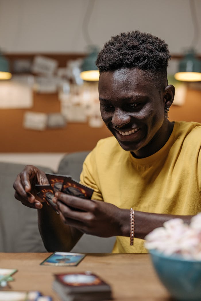 Smiling young man playing cards indoors, captured in a candid moment.