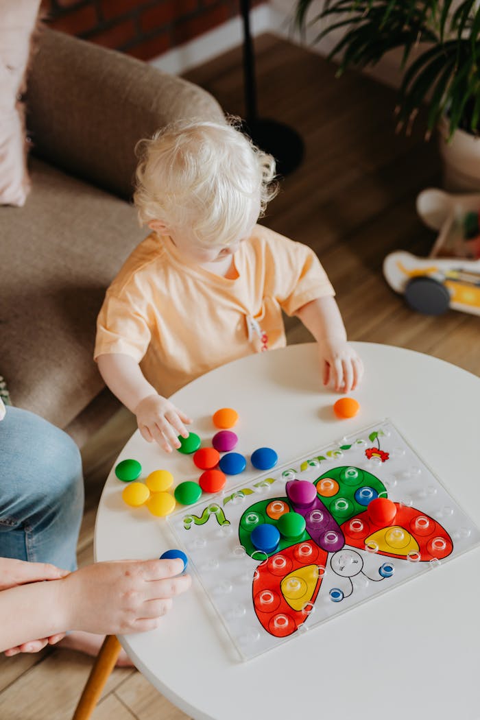 A child with light hair enjoys a colorful educational toy indoors, promoting learning and development.