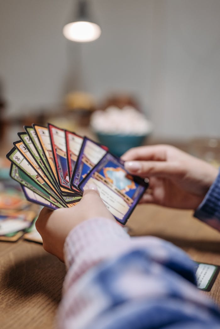 Close-up of hands holding a fan of playing cards indoors with warm lighting.
